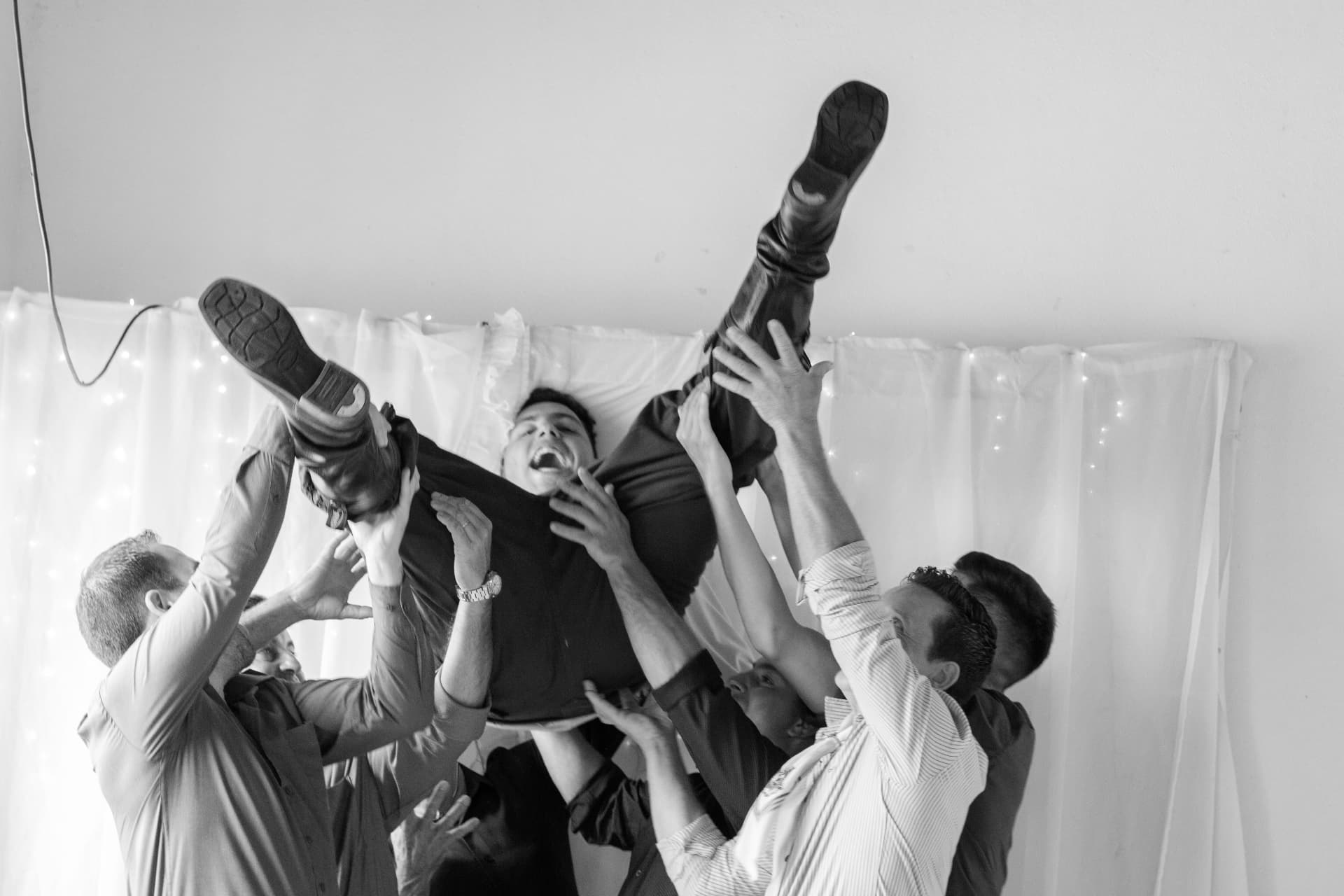 Convidados erguendo o noivo durante a festa, fotografia em preto e branco