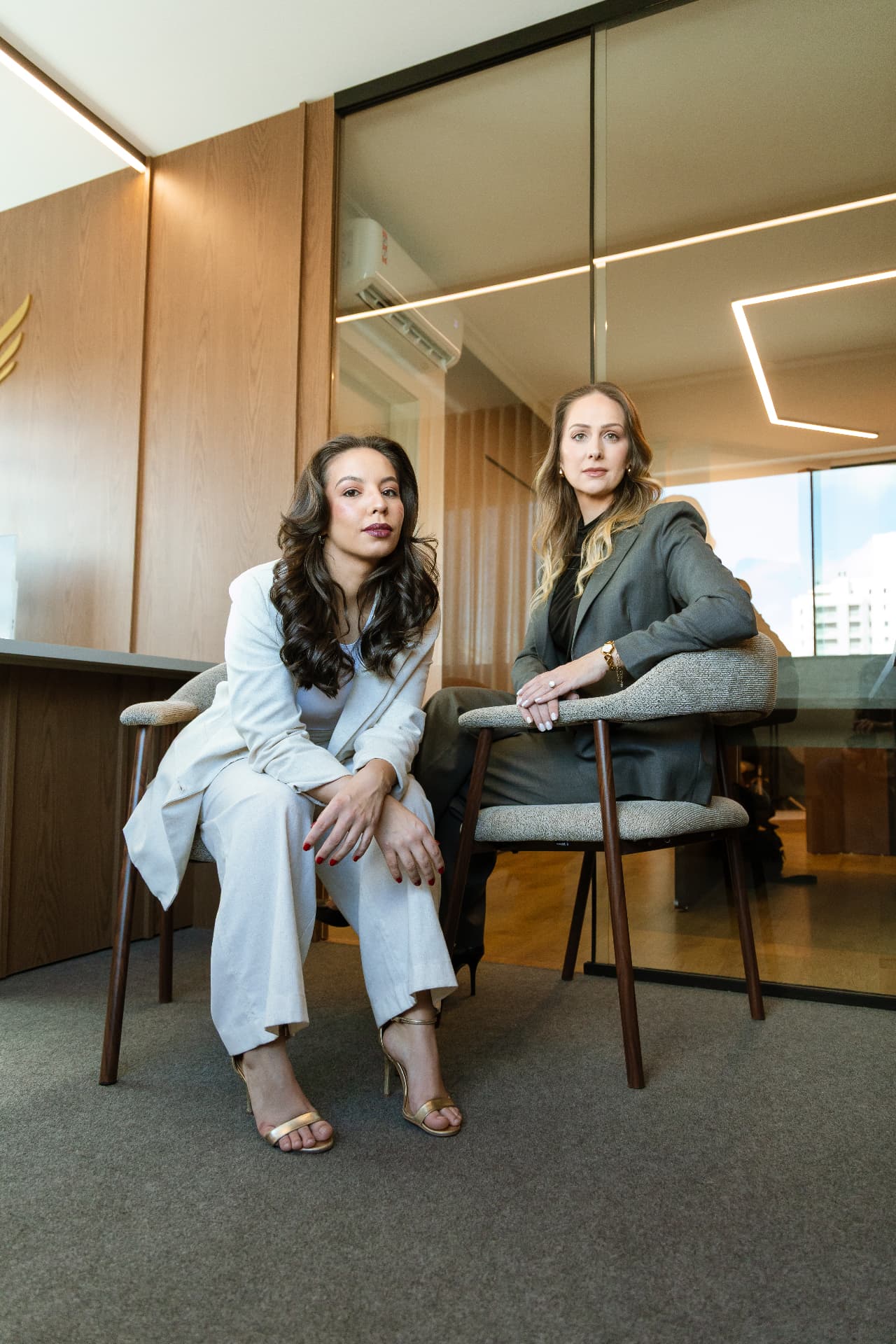 Duas mulheres em retrato corporativo sentadas no escritório